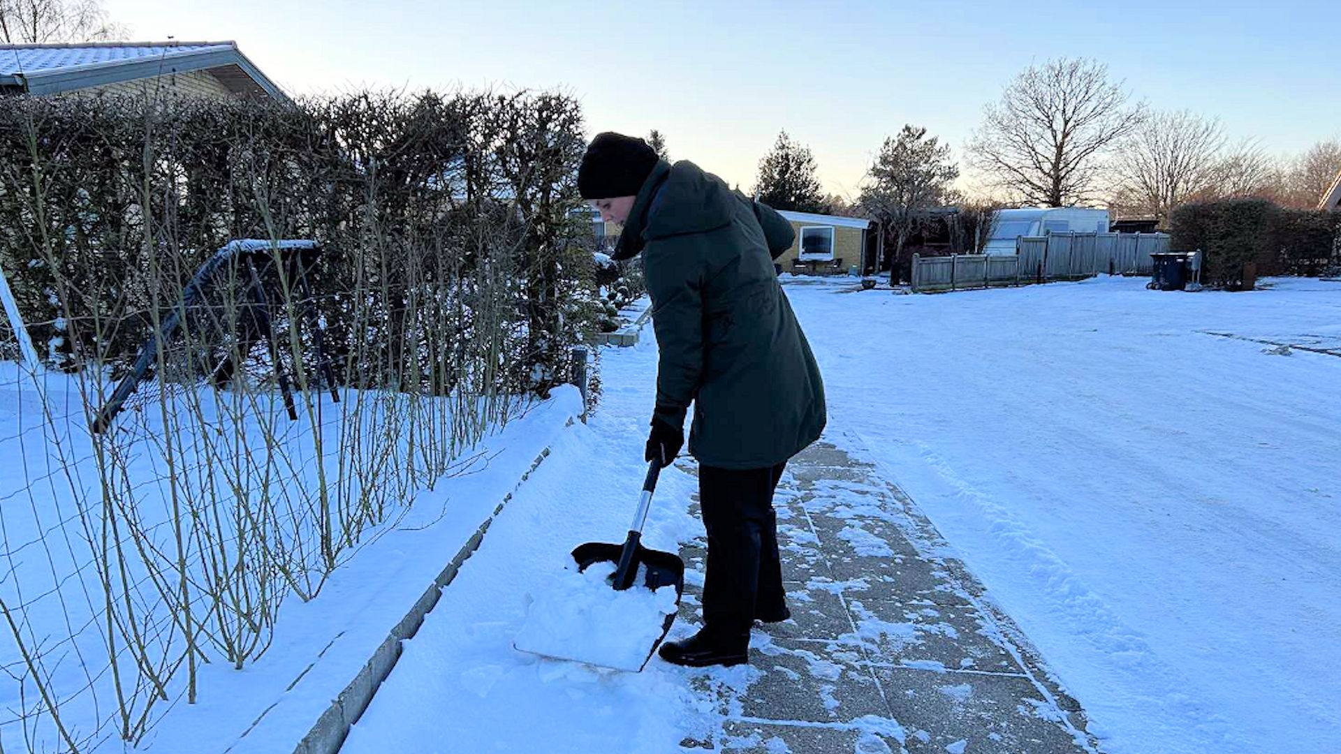 Person rydder sne på fortov