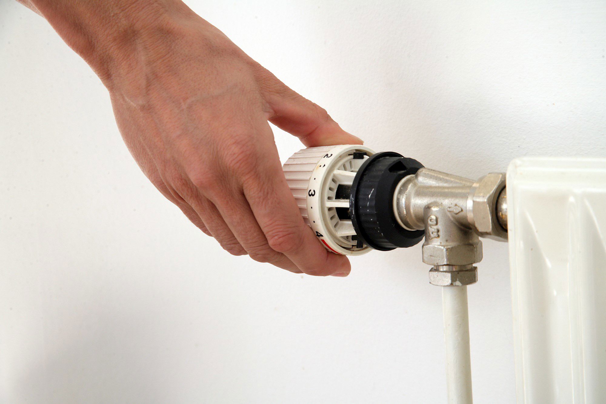 En hånd drejer på en termostat på en radiator