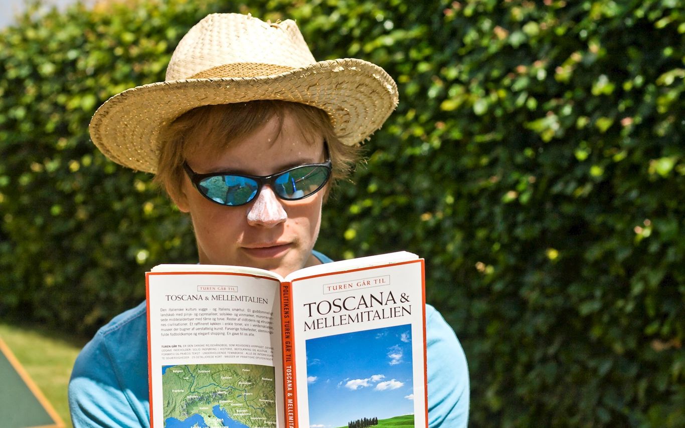 Kvinde læser rejseguide i solskin